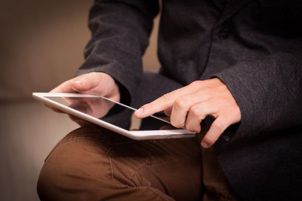 Foto de uma pessoa mexendo em um tablet. Imagem ilustrativa para texto como abrir uma franquia.