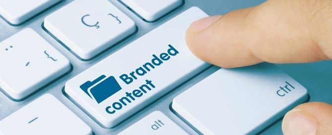 A imagem mostra um zoom em uma das teclas do teclado e um dedo apertando o botão. Na tecla está escrito Branded Content