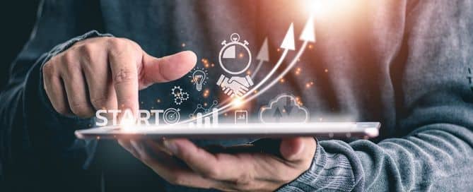 Um homem segura um tablet e há projeções relacionadas com o marketing digital. Destaque para a palavra: START no canto esquerdo da imagem.