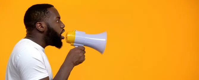 Um homem gritando em um megafone em um fundo amarelo