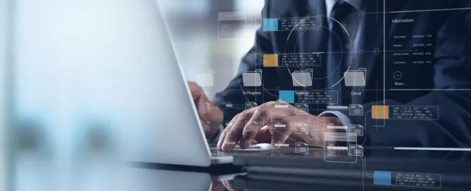 Um homem está digitando em um notebook. Só é possível ver do pescoço para baixo e logo em frente a tela, há projeções de itens de conteúdos