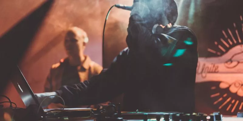 Imagem de um DJ de chapéu fedora, fone ao redor do pescoço e microfone na boca. Faz referência à origem do White Label, justamente com DJs em bailes de hip-hop nos Estados Unidos.