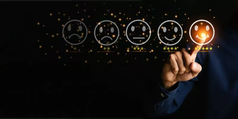Cinco ícones representando notas para um serviço, indo de 1 a 5 estrelas. Ao fundo, uma mão humana toca com o dedo indicador no ícone de 5 estrelas, que possui um sorriso aberto. É uma representação do que acontece quando uma empresa adota a abordagem Customer Centric: a satisfação dos clientes.