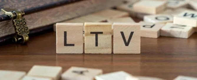Blocos de madeira em cima de uma superfície parecida com uma mesa formando a palavra "LTV", que significa Lifetime Value