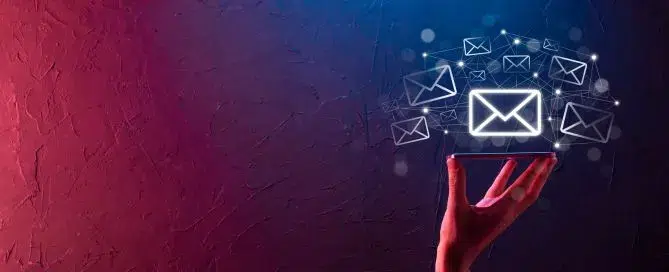 Mão humana segurando celular com diversos ícones de email (mailing) ao redor