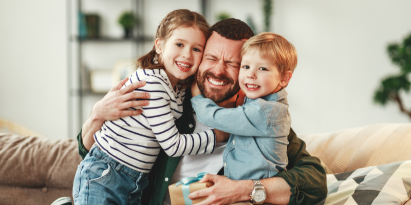 pai e filhos abraçados dentro de casa