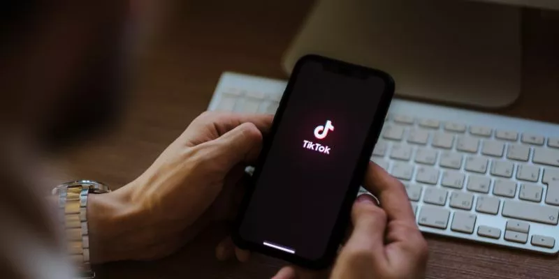 Pessoa segurando um smartphone com o App do TikTok sendo iniciado.