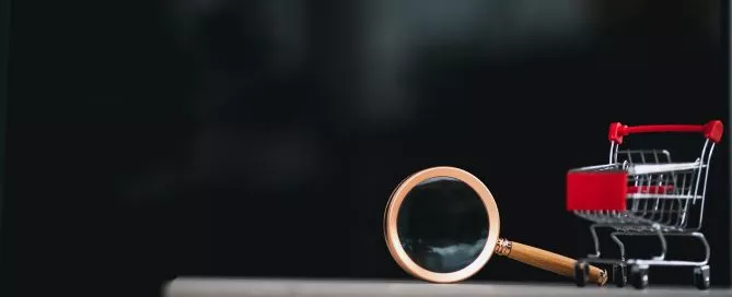 Lupa deitada sobre uma superfície com um carrinho de compras em miniatura, simulando a ação de um cliente oculto.