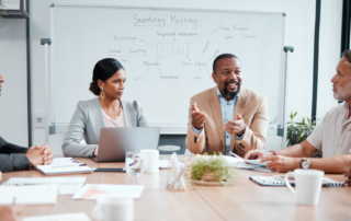 A imagem mostra uma equipe em volta de uma mesa de reunião conversando