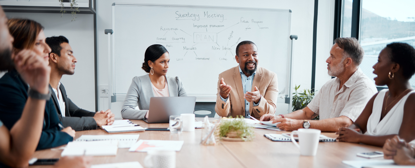 A imagem mostra uma equipe em volta de uma mesa de reunião conversando